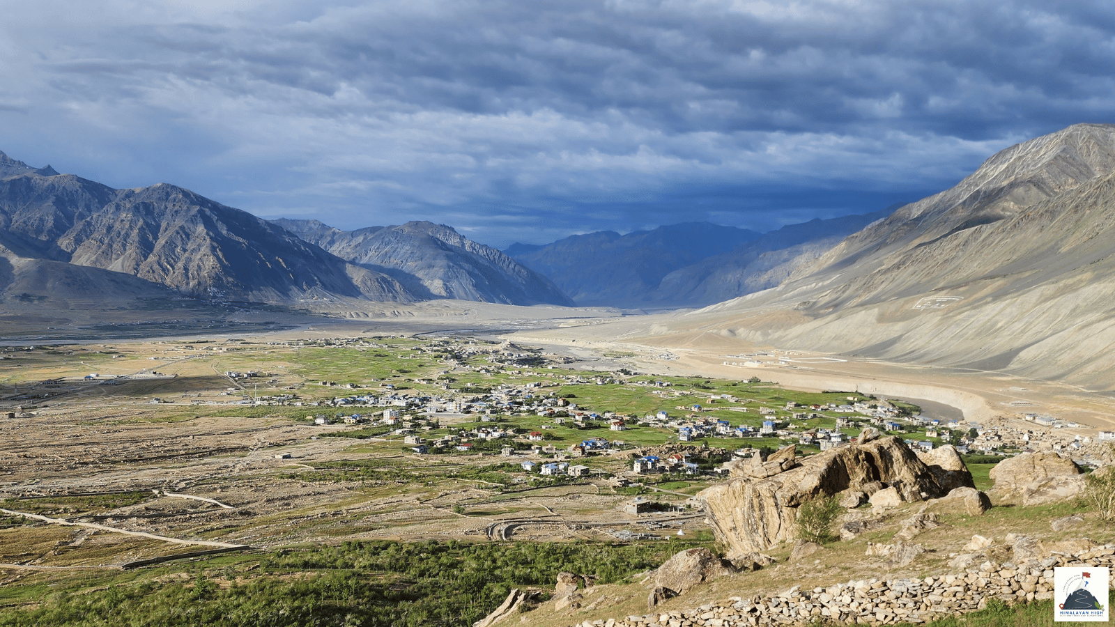 Padum spread across the green Zanskar valley floor below bare mountains and a stormy sky