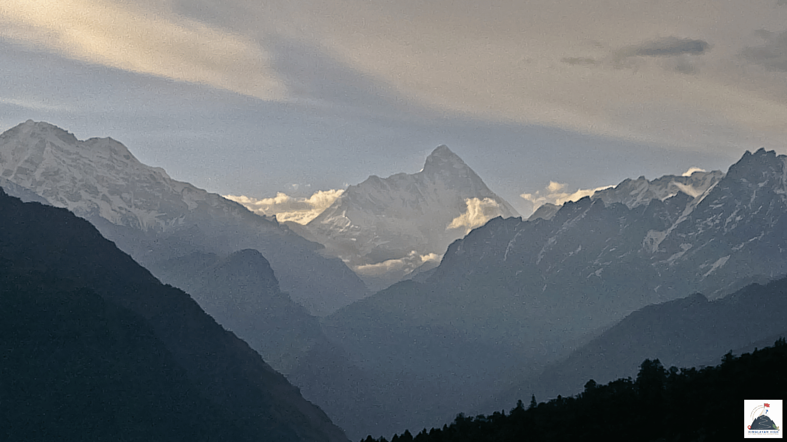 Nanda Devi's pointed summit rising beyond layered blue ridges, seen from Auli