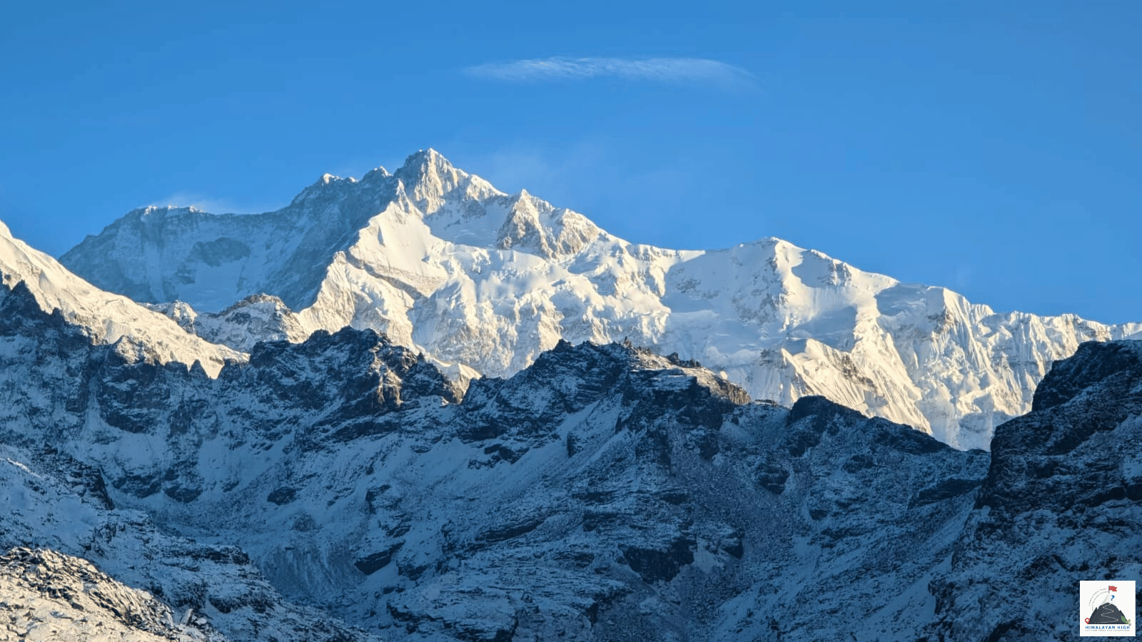 Kanchenjunga's summit in morning light above snow-dusted rock ridges