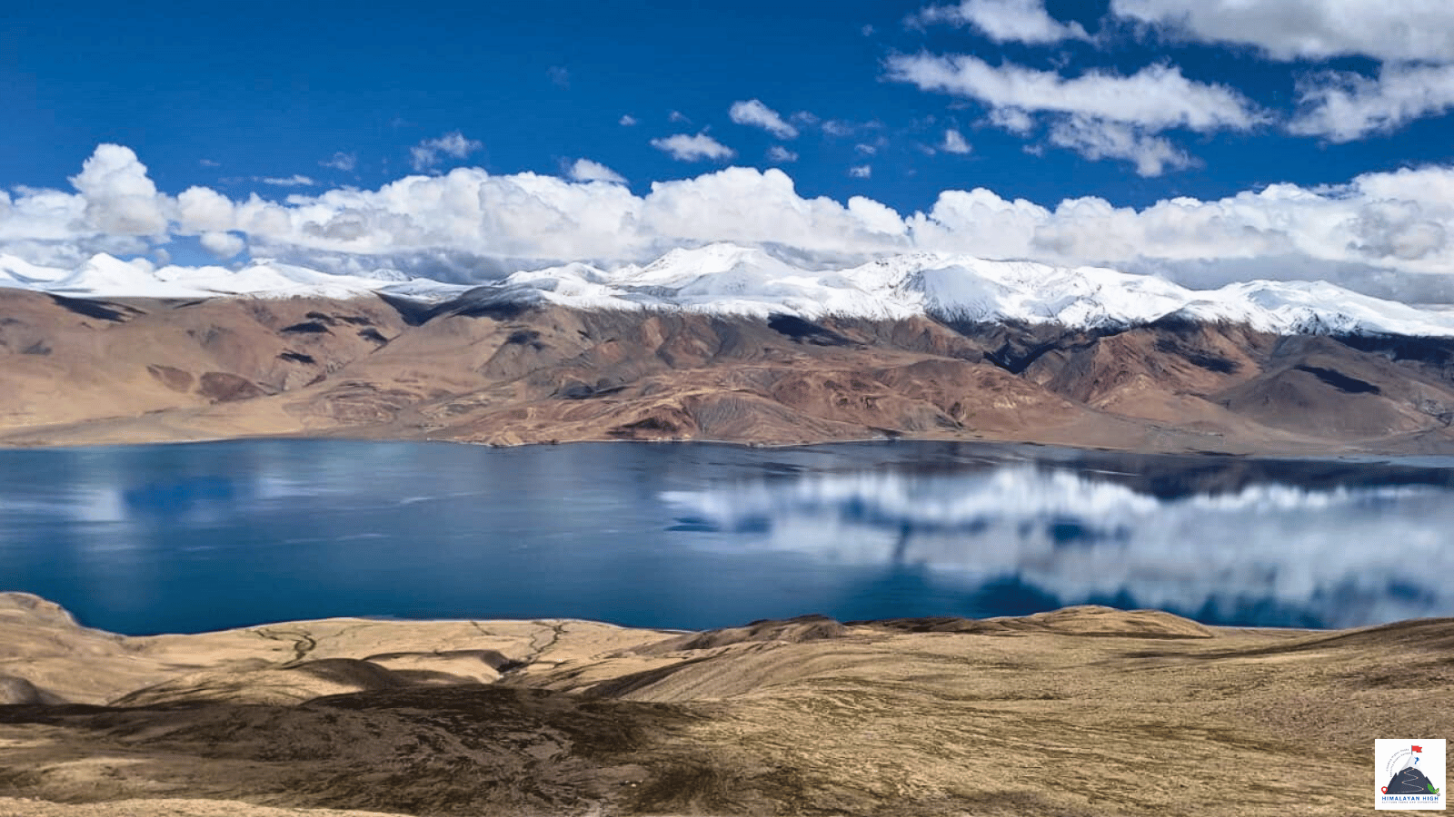 Tso Moriri’s blue water reflecting clouds below snow-capped ridges